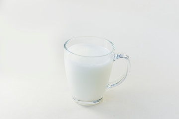 A cup of soy milk stands alone on a pale yellow background.