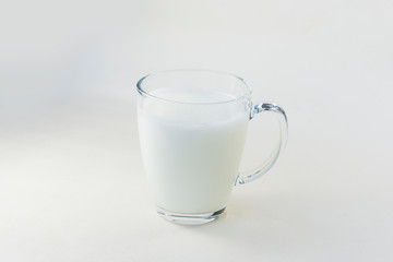 A cup of soy milk stands alone on a pale yellow background.