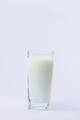A cup of soy milk stands alone on a pale yellow background.