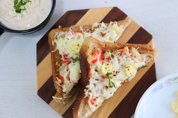 Chili Cheese toast, Open cheese sandwich or mini bread pizzas served with mayonnaise deep and garnished with chopped Basil leaves.