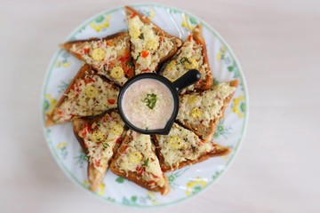 Chili Cheese toast, Open cheese sandwich or mini bread pizzas served with mayonnaise deep and garnished with chopped Basil leaves.