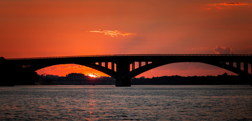 Fototapeta na wymiar Cityscape of bridge and sunset; view of the purple sky through the arch of the bridge.