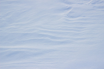 Natural winter background with snow drifts. Background of fresh snow texture in blue tones. High angle view of snow texture, background with copy space.