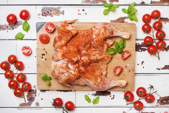 Raw chicken tobacco on a wooden Board with spices and vegetables.