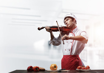 Young male chef with violin standing