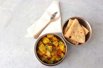 Stainless steel Lunch Box or Tiffin with Indian food menu Chapati or Roti, Garlic Dal Tadka, White Rice and Potato or Jeera aloo. with spoons, tissue paper and glass of water. Copy space