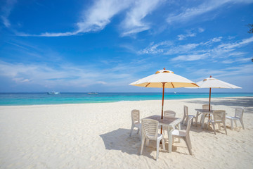 Empty tables and chairs with umbrella on the beach, near the sea.
