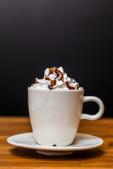 cup of coffee with whipped cream on wooden background