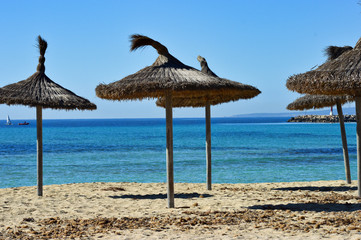 Wooden umbrellas on the empty sandy beach on Mallorca Islands in Spain