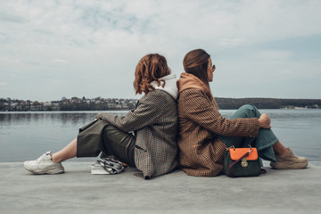Portrait of Two Fashion Girls, Best Friends Outdoors, Wearing Stylish Jacket, Walking Near the Lake