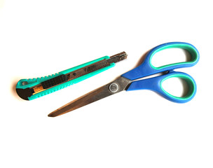 Green stationery knife and blue scissors on a white isolated background. Place for text.