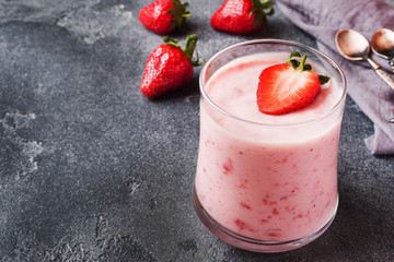 Homemade yogurt with fresh strawberries in glasses on a dark concrete background. Selective focus. Copy space.