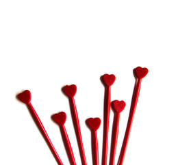 Red plastic sticks for canapes with a heart on a white isolated background. Copy space.