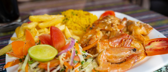 Delicious dish on restaurant table. Closeup plate of yummy dish with shrimps and french fries placed on ornamental table in cafe