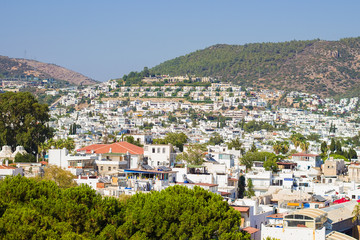 Fototapeta na wymiar Panoramic view from the walls of Bodrum castle (also known as St Peter Castle) in Bodrum. Famous white cubic buildings, blue Aegean sea and green nature on the background, Mugla, Turkey.