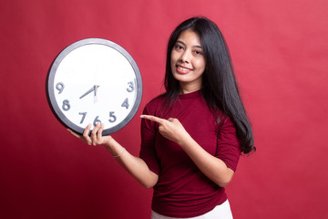 Young Asian woman point to a clock.