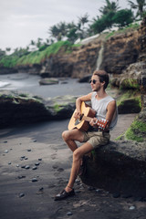 Romantic young man with a guitar on the beach