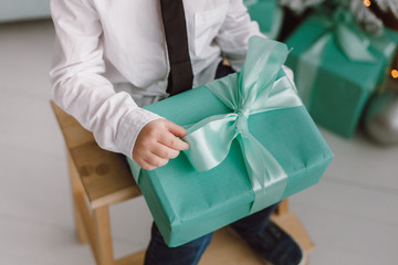 Beautiful gift box with a bow close-up in the hands of a child. The concept of the new year.