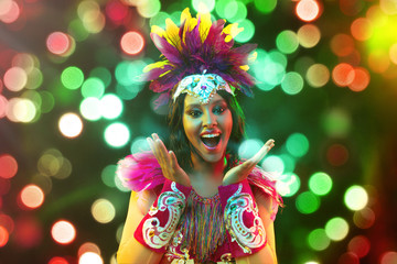 Beautiful young woman in carnival mask and stylish masquerade costume with feathers and sparklers...