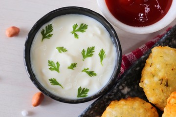 Sabudana vada or Sago fried fitters served with Curd or yogurt and ketchup over white wooden background, popular fasting recipe from India or mostly eaten during Fasting