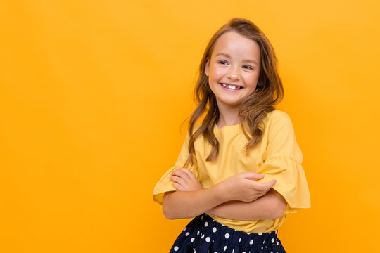 Pretty little girl in beautiful dress rejoices of her life isolated on orange background