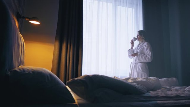 Beautiful woman in a white bathrobe drink coffee and enjoy a wonderful morning in the hotel room