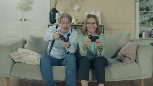 Elderly man and woman are playing a videogame at home