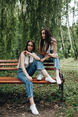 Portrait of Two Young Brunette Twins Sisters Dressed Alike in Jeans and White T-shirt, Best Friends Forever Concept