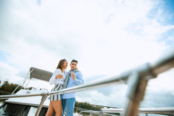 Lovers spending happy time on a yacht at sea. Luxury honeymood on a seaboat. Vacation, travel, sea, friendship and people concept. Smiling couple sitting and talking on yacht deck