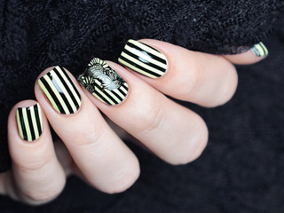 Bright yellow manicure with black stripes and sunflowers pattern on black background
