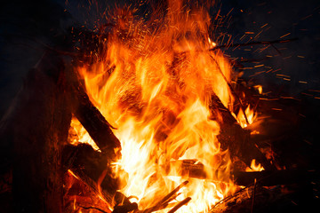 Colorful flame and sparks from a bonfire on a dark background