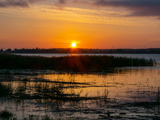 Fototapeta na wymiar landscape with sunset in the background, lake sand and grass in the foreground