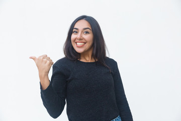 Happy joyful woman pointing thumb away. Beautiful young woman in casual sweater posing isolated over white background. Advertising concept