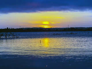 Naklejka premium landscape with sunset in the background, lake sand and grass in the foreground