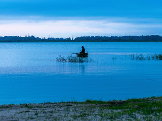 evening light on the lake, fisherman in boat, dusk