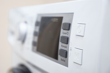 empty screen and buttons on control panel of modern washing machine on blurred background close view