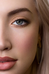 Fototapeta premium Half a beauty portrait with beautiful fashionable day make-up, black jiggles on eyes and extremely long eyelashes. natural lipstick on the lips. Cosmetology and spa facial skin care