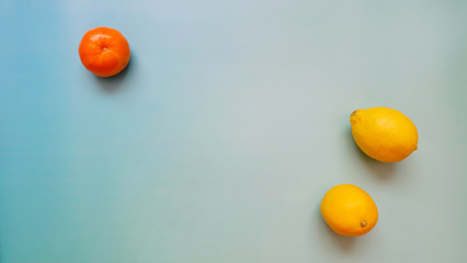 Top view of one mandarin orange and two lemons, with copy space in the middle. 
