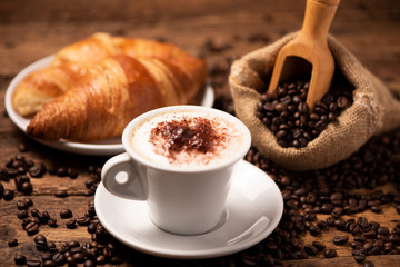 A cup of cappuccino with coffee bean as background.