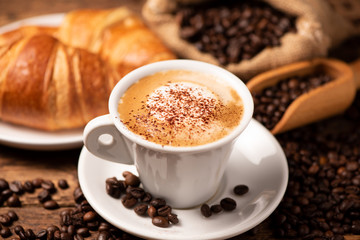 A cup of cappuccino with coffee bean as background.