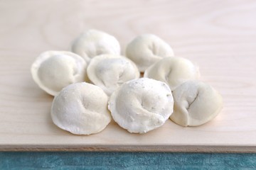 Fototapeta na wymiar Dough product: dumplings in flour on wood board before putting in cooking water