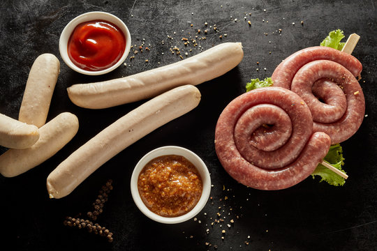Assorted raw sausages with trimmings in bowls