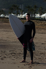 Caucasian boy with a black neoprene prepared to surf .