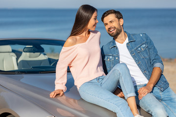 asian girl and caucasian guy looking at each other while leaning the convertible