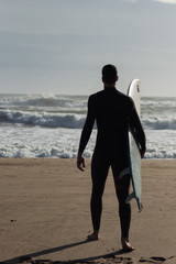 Caucasian boy with a black neoprene prepared to surf .