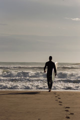 Caucasian boy with a black neoprene prepared to surf .