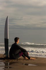 Caucasian boy with a black neoprene prepared to surf .
