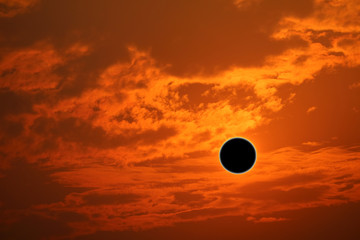 Obraz premium phenomenon of partial sun eclipse over silhouette orange cloud and sunset sky