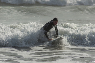 Caucasian boy with a black neoprene prepared to surf .