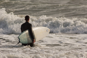 Caucasian boy with a black neoprene prepared to surf .